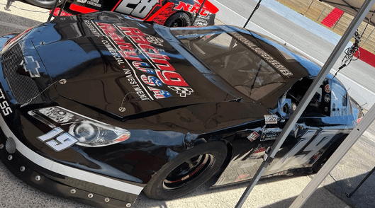 Chris Burns's black No. 19 Late Model in the pits under a canopy